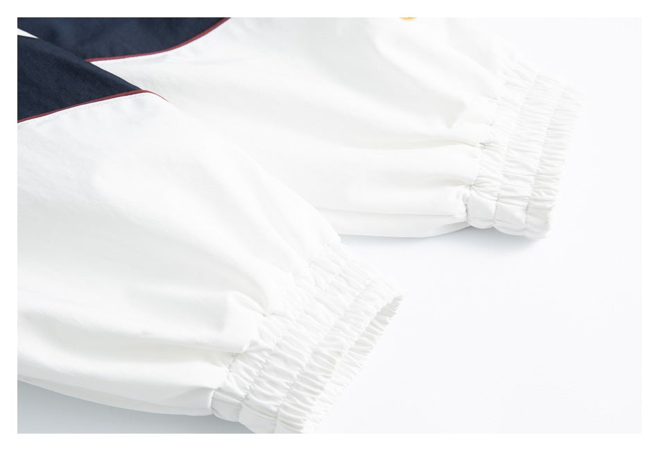 Close-up of two white sleeves with gathered elastic cuffs and navy panels edged in burgundy.