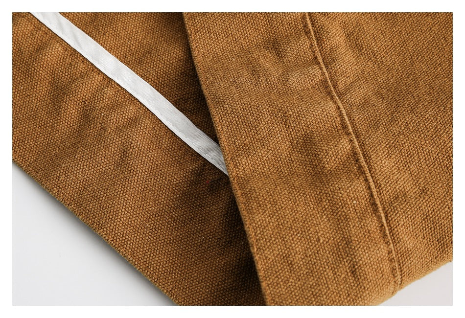 Close-up of camel-brown garment fabric, a stitched edge and a strip of white lining.