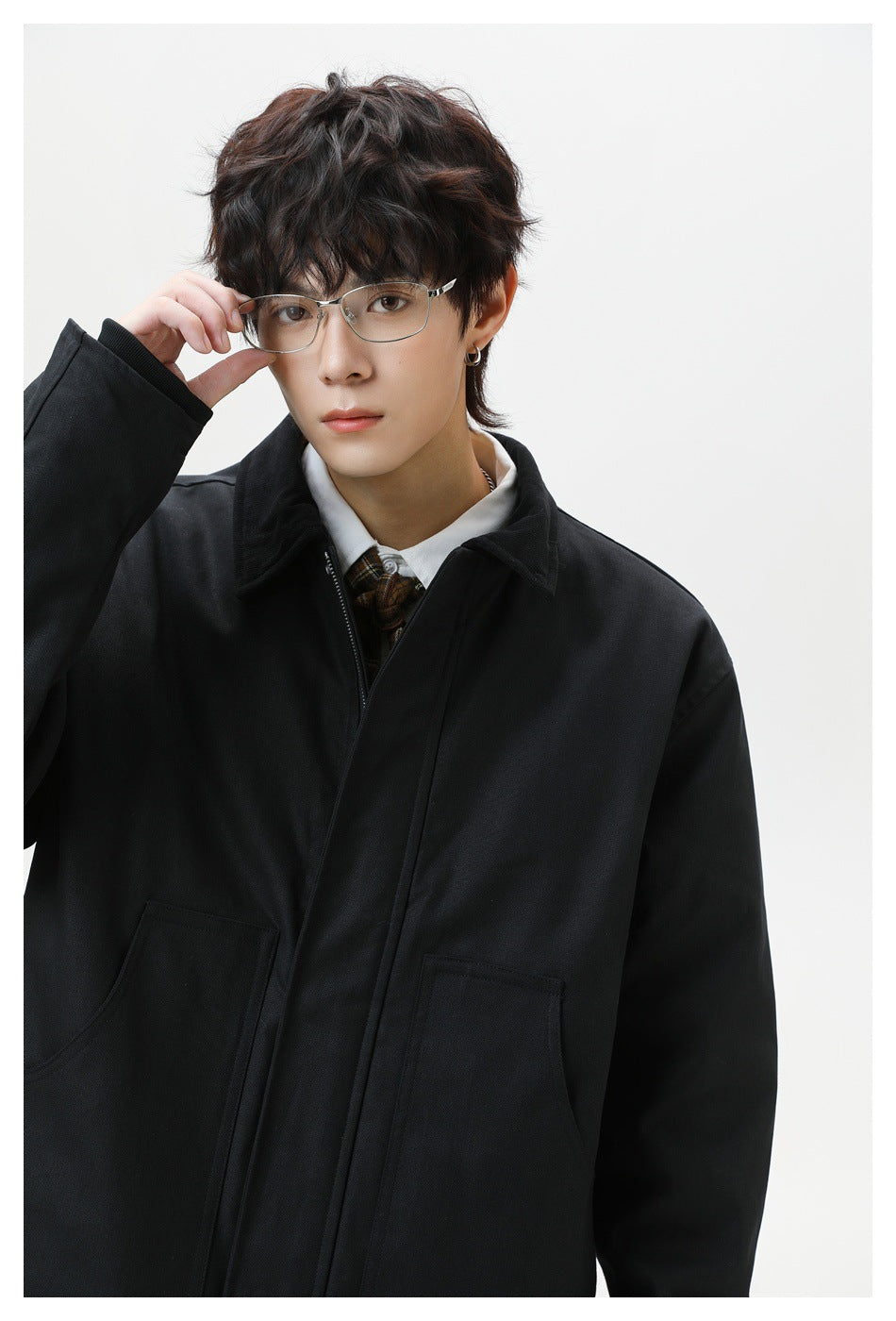 Close-up of a model wearing a black collared jacket with a front zipper and large patch pockets.