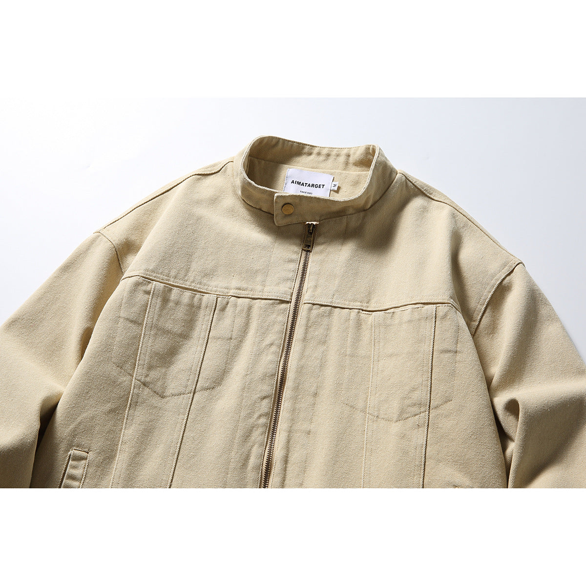 Close-up of a sand-colored jacket’s stand collar, snap tab, zipper, and sewn neck label.