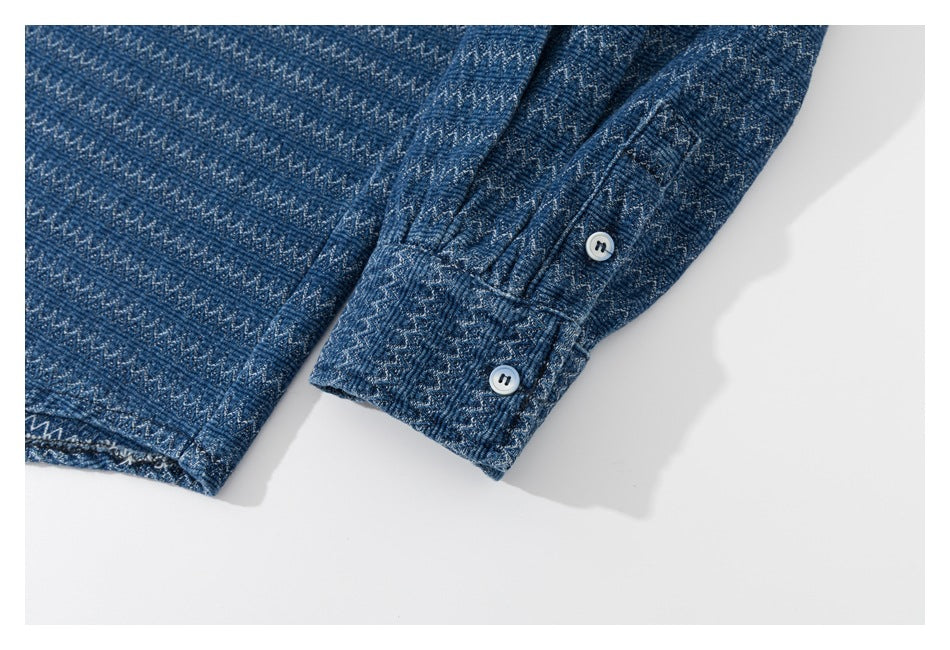 Close-up of a blue patterned garment cuff with two light-colored buttons and stitched detailing.