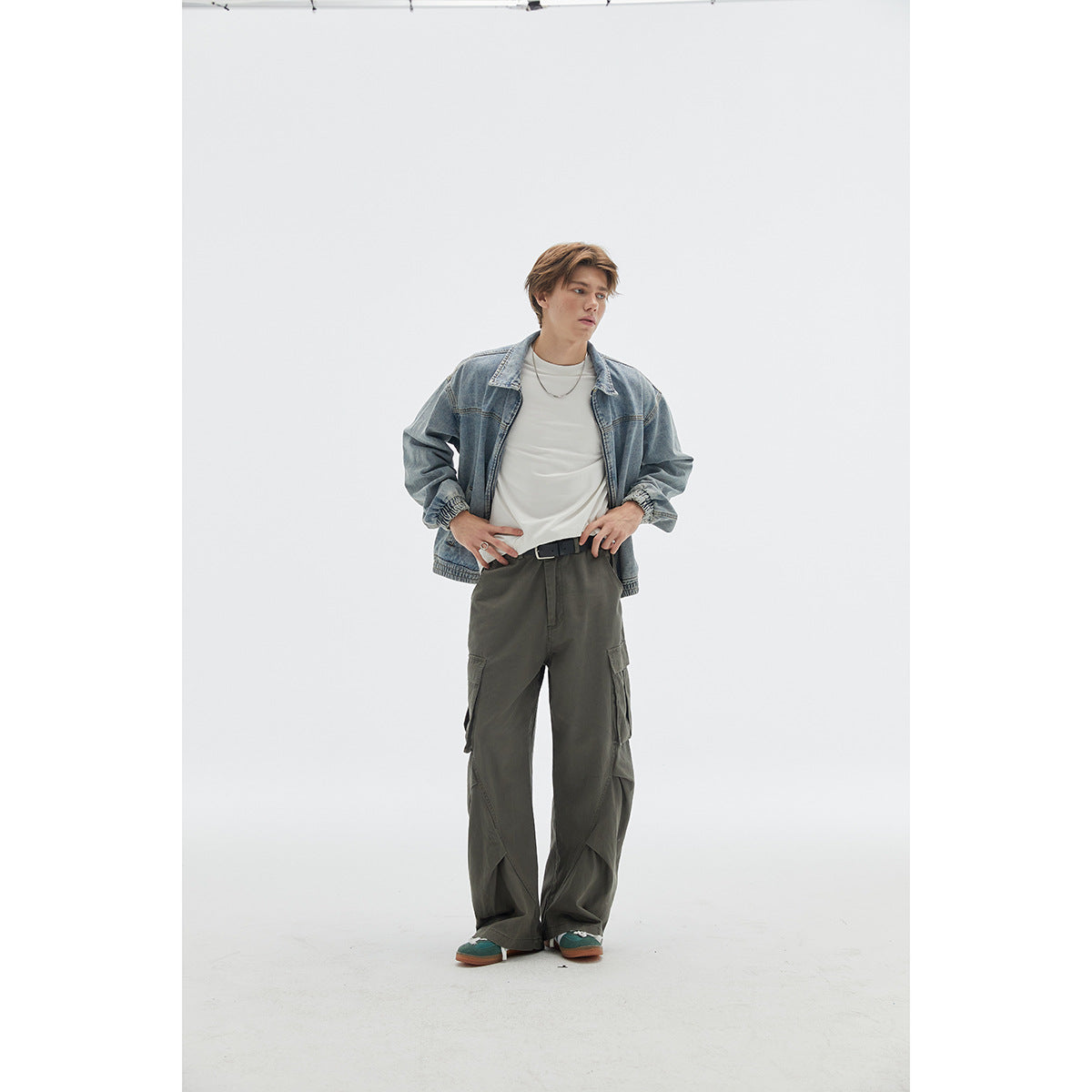 Model wearing a light-wash blue denim jacket over a white shirt with loose dark cargo pants.