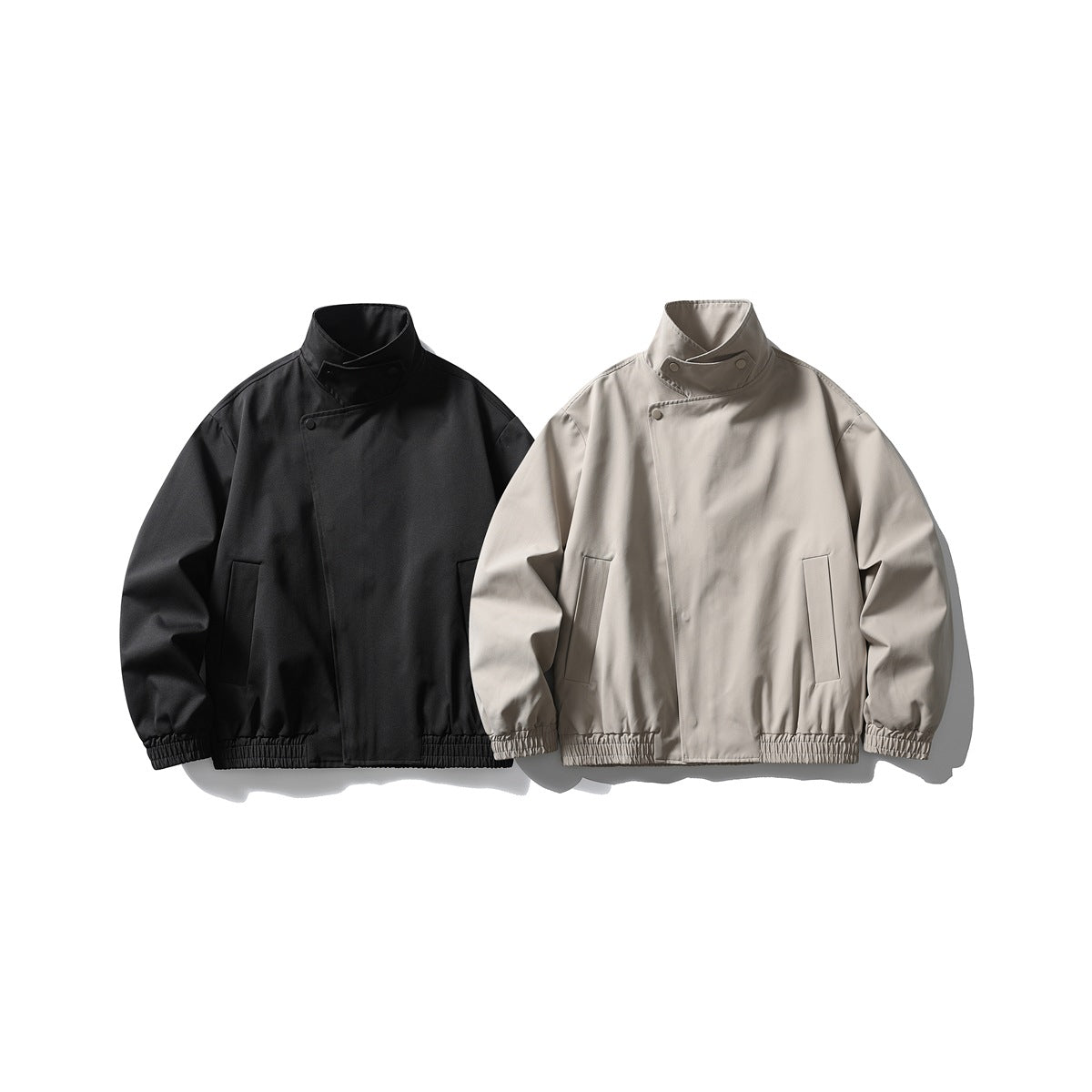 Front view of two high-collar jackets with snap details, one black and one light taupe.