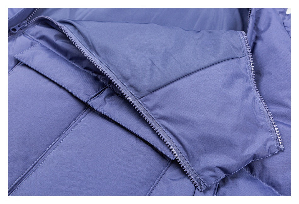 Close-up of an open periwinkle garment zipper beneath a wide fabric storm flap.