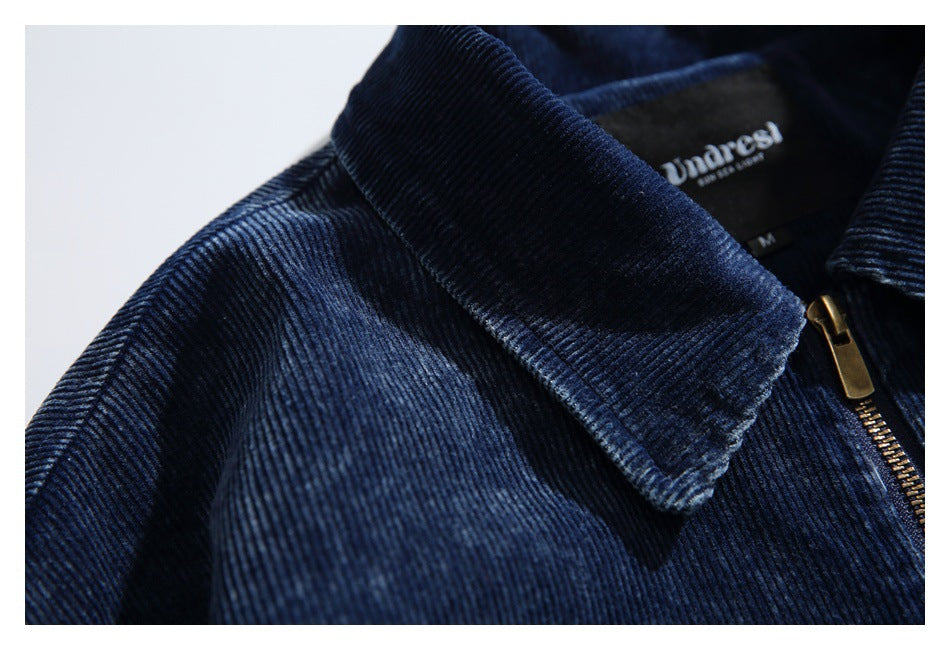 Close-up of the navy corduroy collar, shoulder seam, and brass zipper pull.