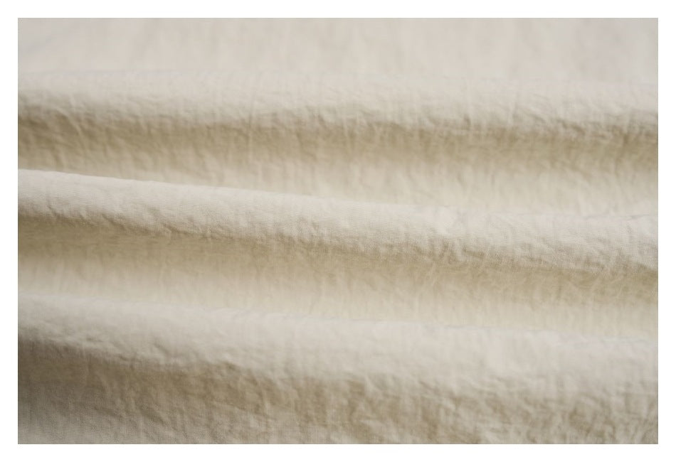 Extreme close-up of softly wrinkled ivory fabric folds.