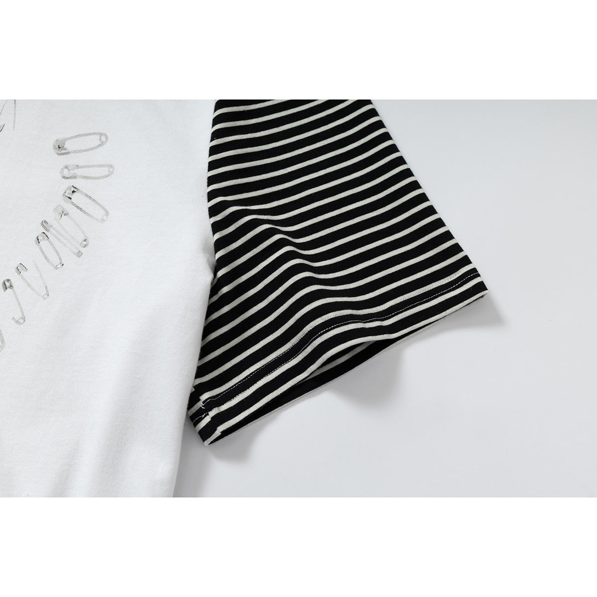 Close-up of a black sleeve with narrow white stripes beside the white body of a T-shirt.
