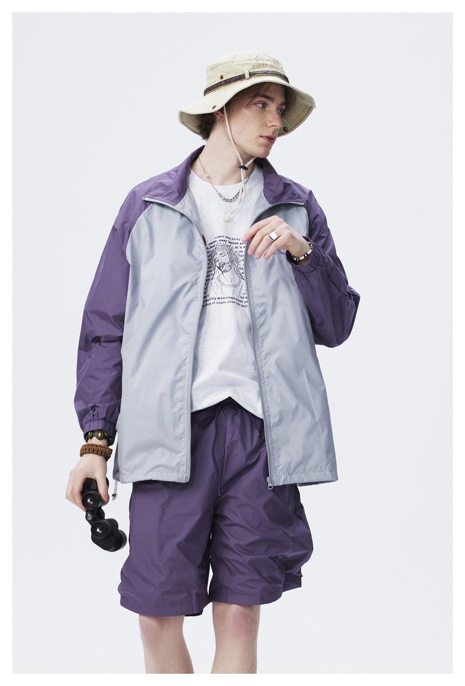 Model wearing an open light gray jacket with purple sleeves and matching shorts.