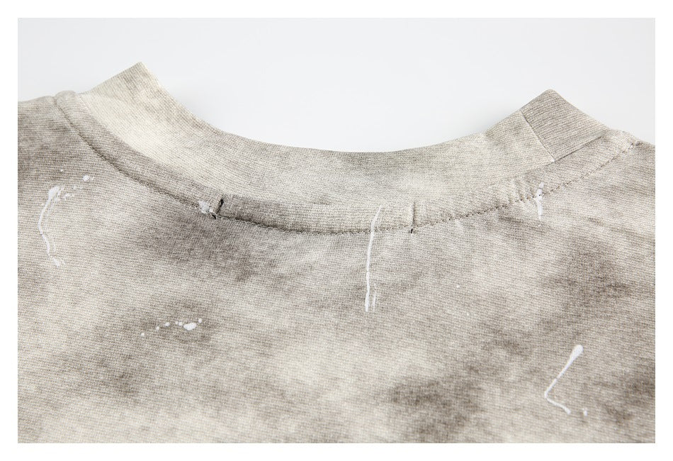 Close-up of a gray-beige mottled garment's crew neckline with scattered white marks.
