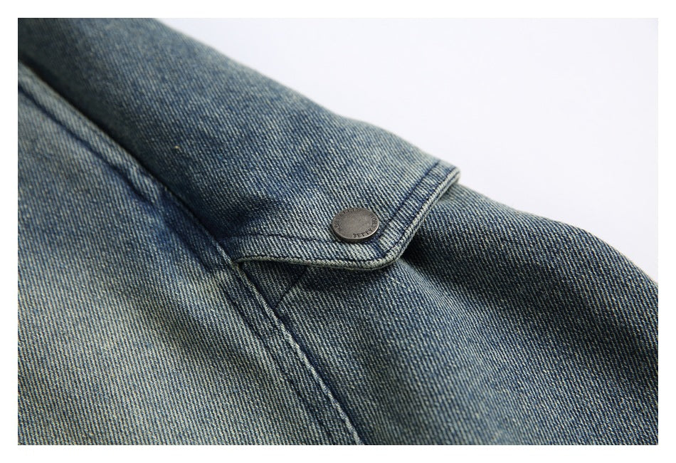 Close-up of a small buttoned denim tab and seam on blue denim pants.