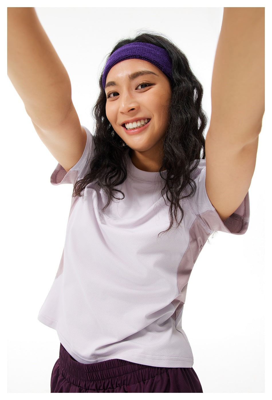 Close-up front view of a woman wearing a light lavender short-sleeve shirt with mesh side panels.