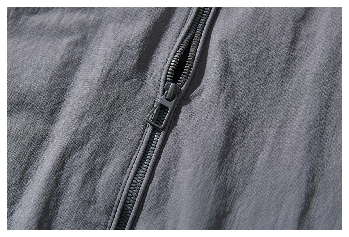 Close-up of the jacket’s dark gray front zipper and pull against charcoal gray fabric.