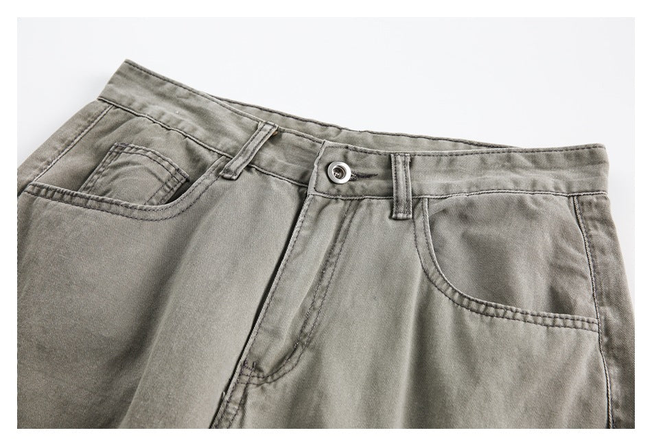 Close-up of gray pants showing the button waistband, belt loops, fly, and curved front pockets.