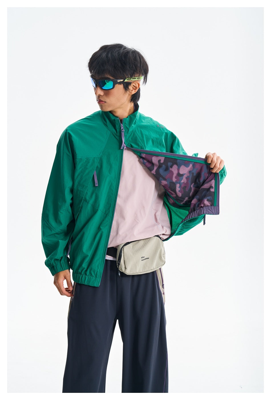 Close view of a model opening a teal-green jacket to show its purple patterned lining and zipper details.