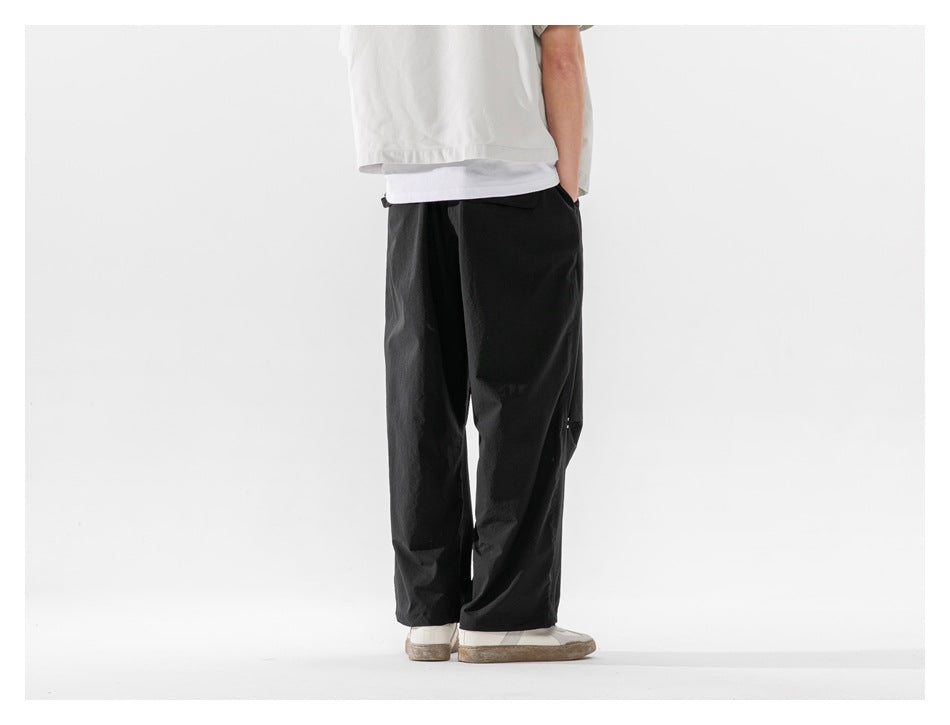 Back view of a model wearing loose black trousers with straight, wide legs.