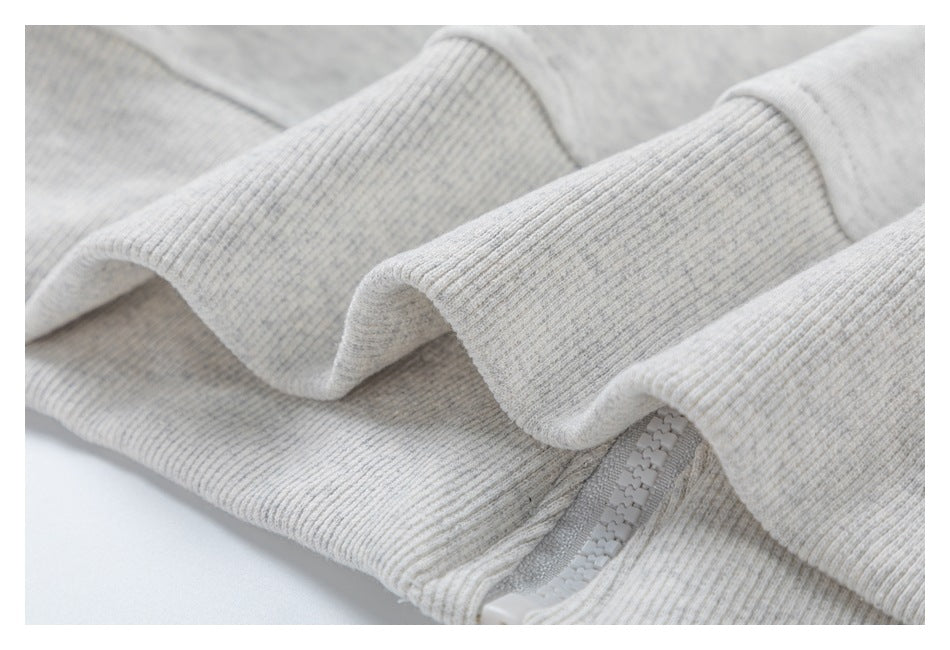 Close-up of ribbed trim and zipper on a light heather-gray hoodie.