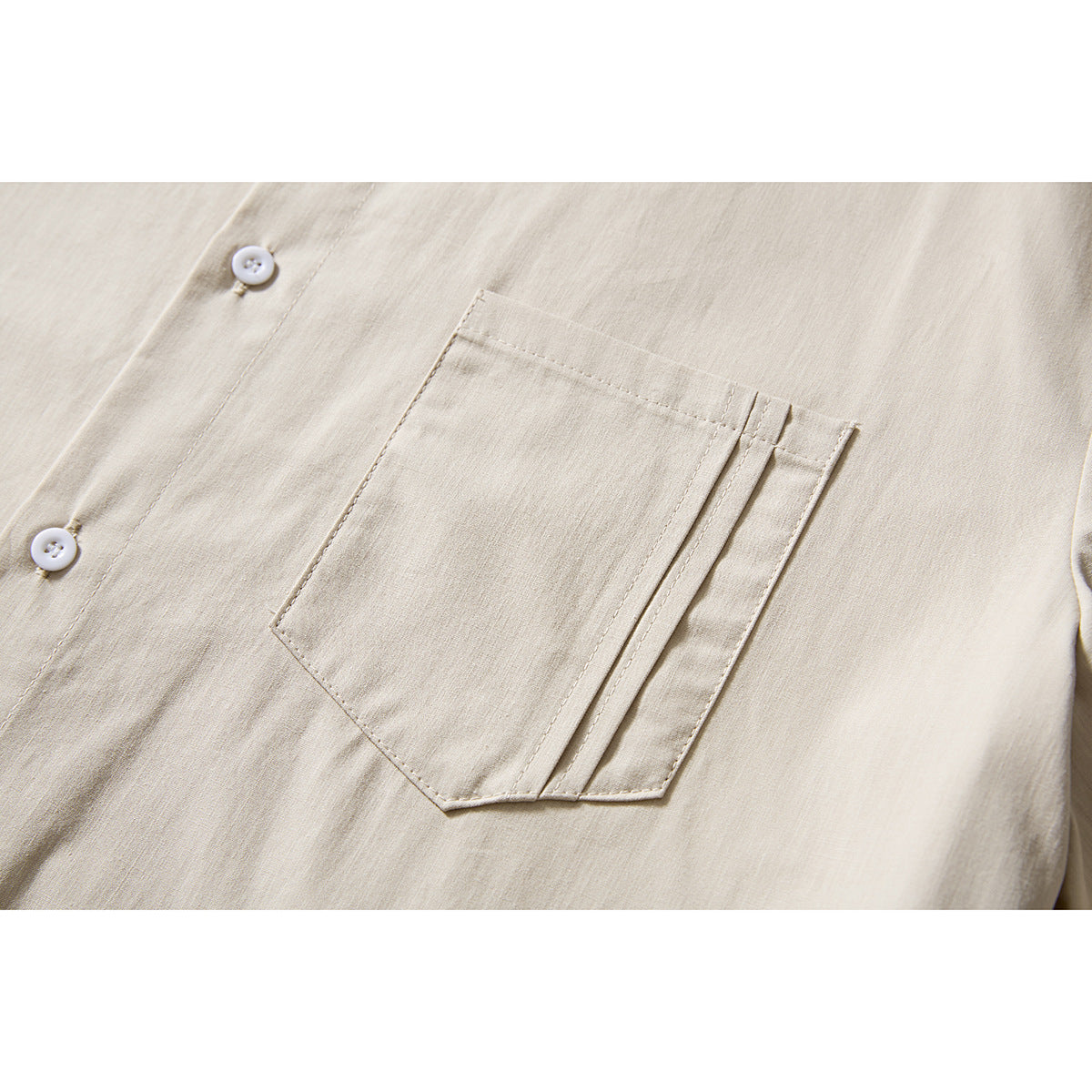 Close-up of a beige shirt's stitched chest pocket and white front buttons.