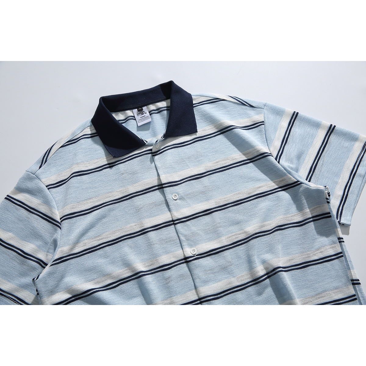 Flat-lay front of a pale blue and white striped short-sleeve polo with a navy collar and button placket.