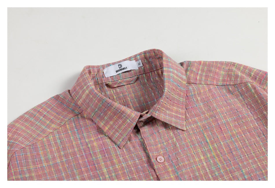 Close-up of the pointed collar and upper chest of a pink plaid button-up shirt laid flat.