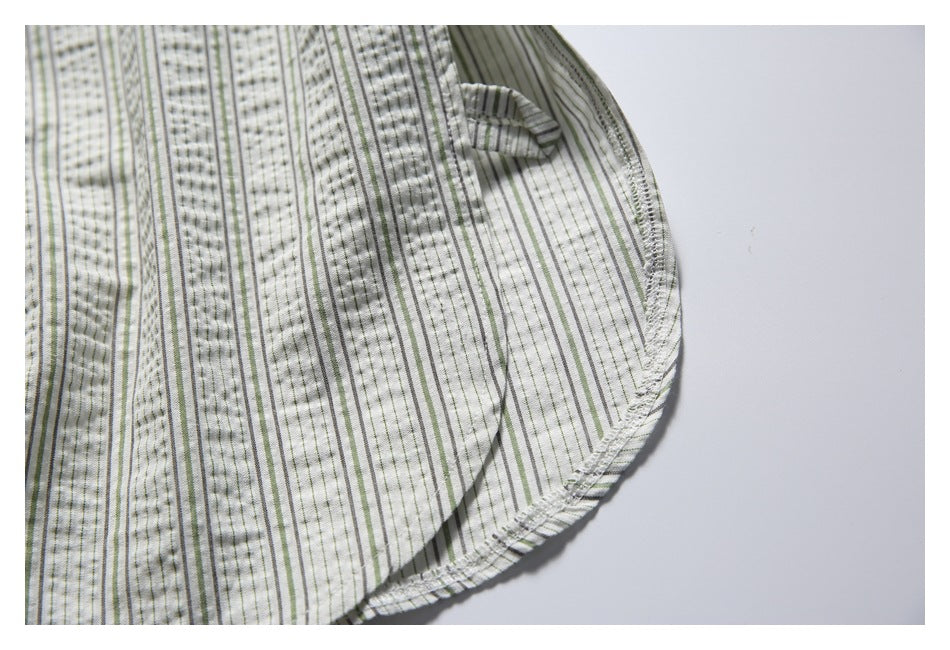 Close-up of the curved hem of a white shirt with narrow green and gray stripes and visible stitching.