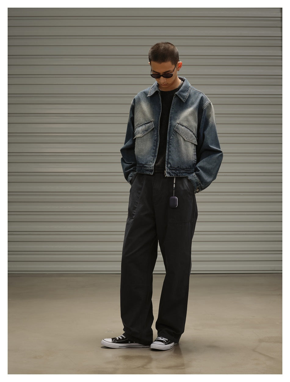 Model wearing a faded blue denim jacket with flap chest pockets and loose black trousers, front view.