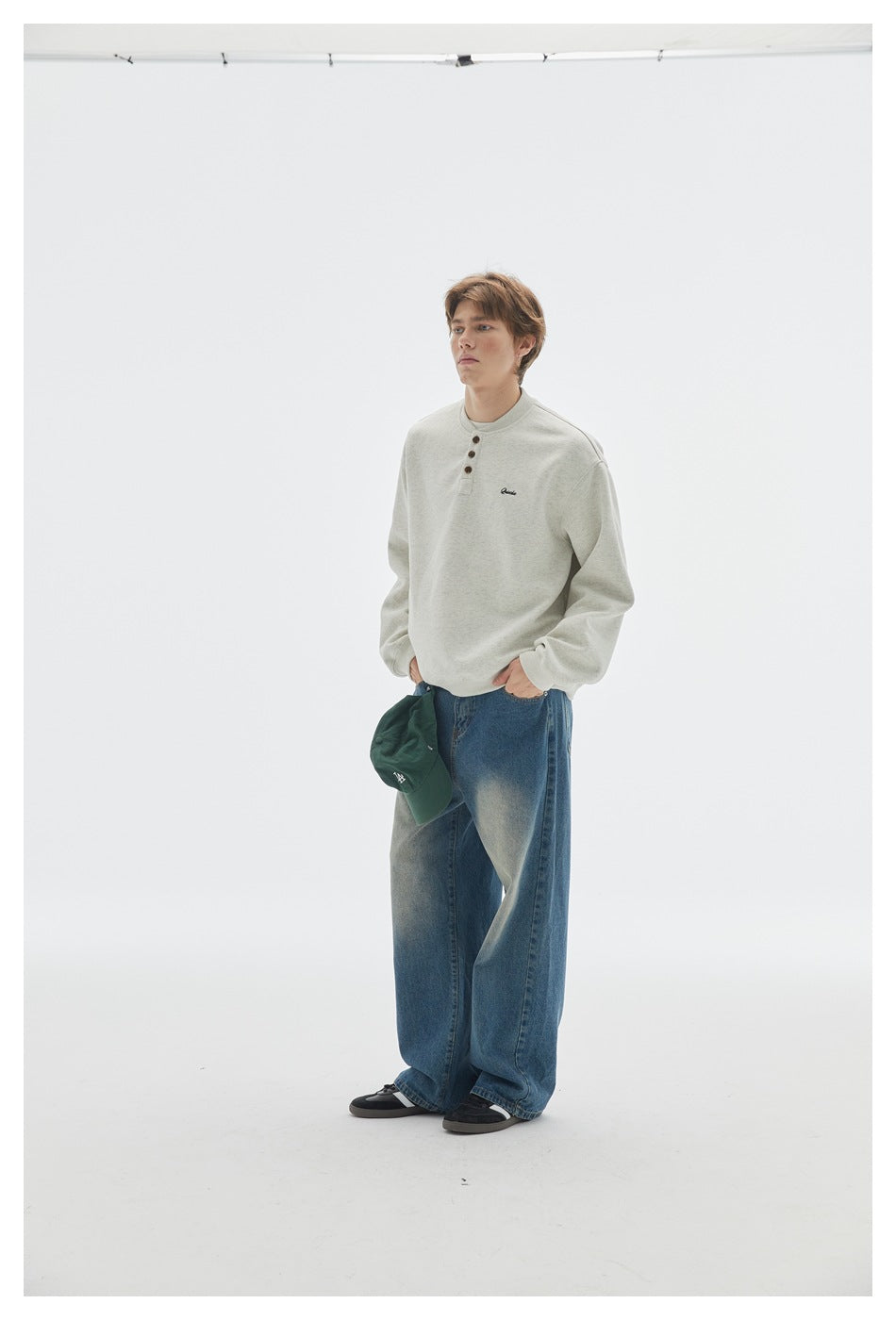 Model in light heather gray henley sweatshirt and faded jeans, hands in pockets, three-quarter view