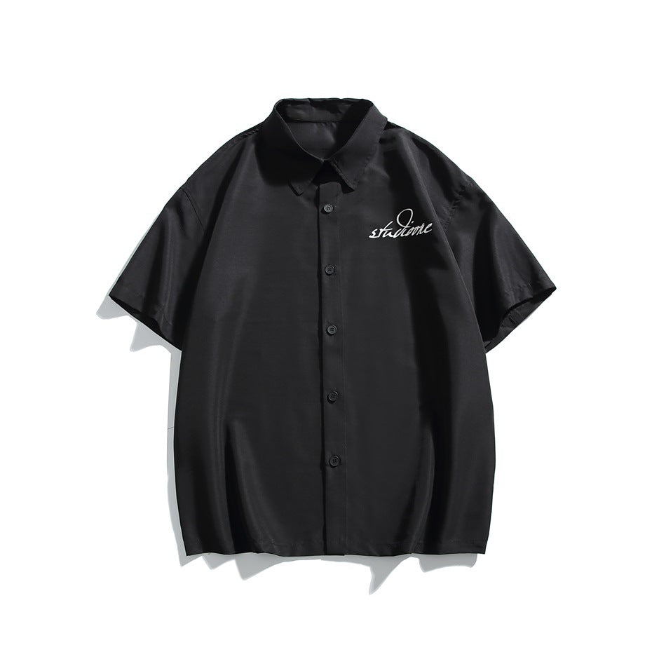 Black short-sleeve button-up shirt with white script graphic on the left chest, flat front view