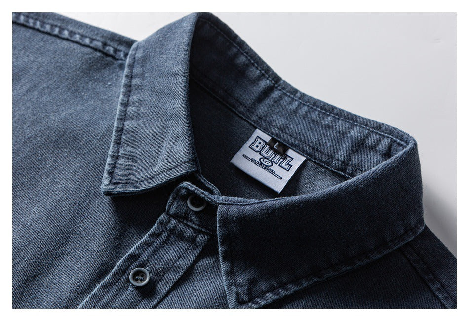 Close-up of a dark blue shirt's pointed collar, buttons, and inner neck label.