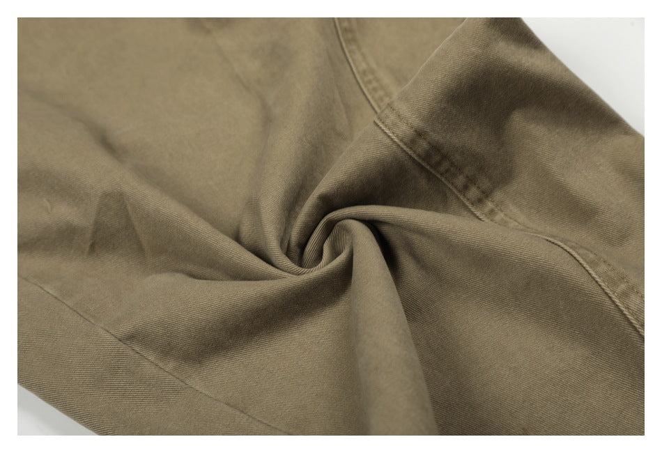 Close-up showing the taupe trousers' fabric, stitching and soft folds.