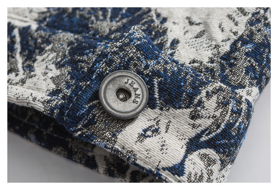 Metal button engraved with “JEANS” against blue and ivory patterned garment fabric.
