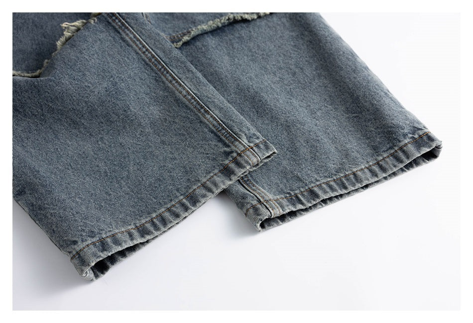 Close-up of the overlapping legs and stitched hems of blue-gray jeans.
