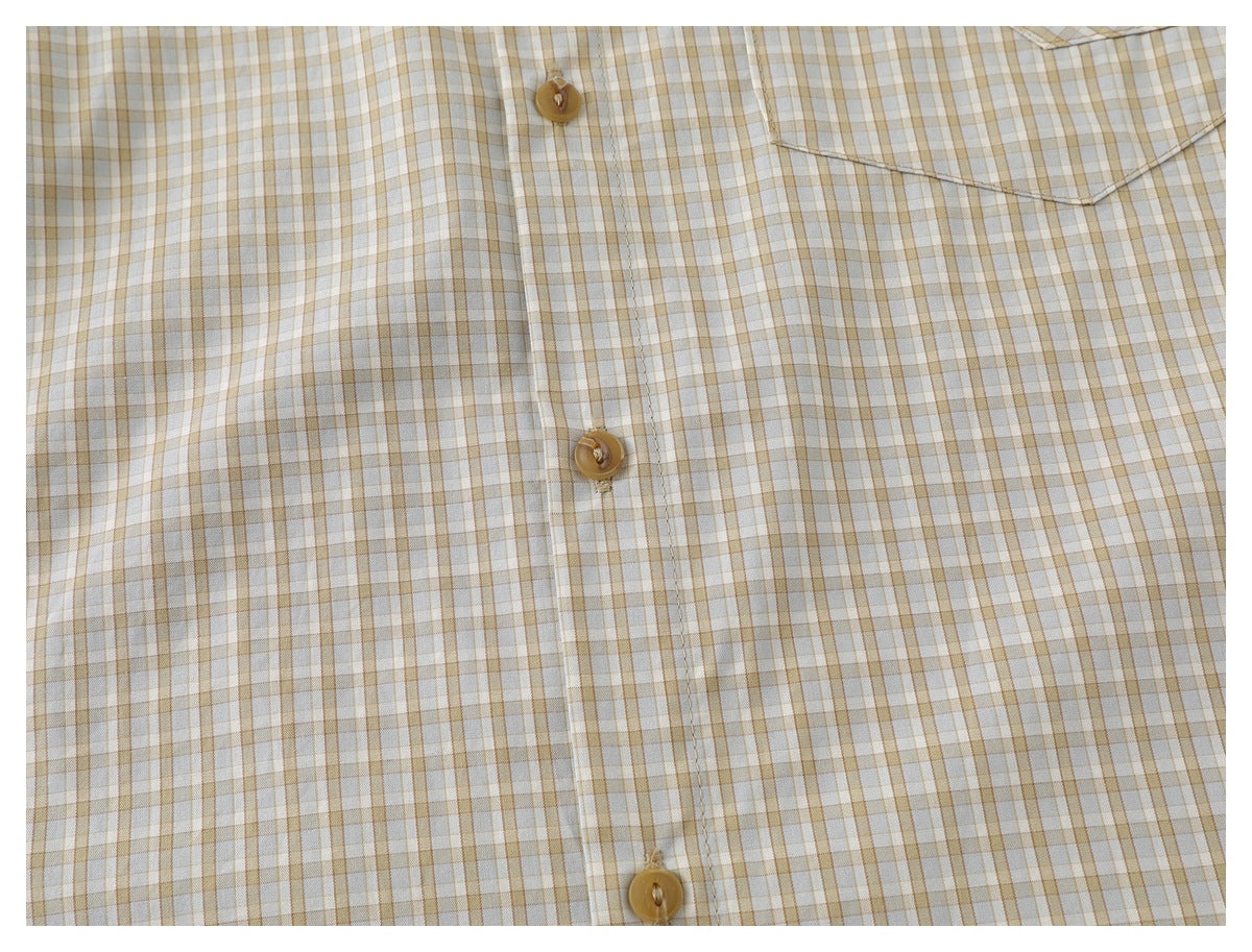 Close-up of a beige plaid shirt front showing tan buttons and a chest pocket.