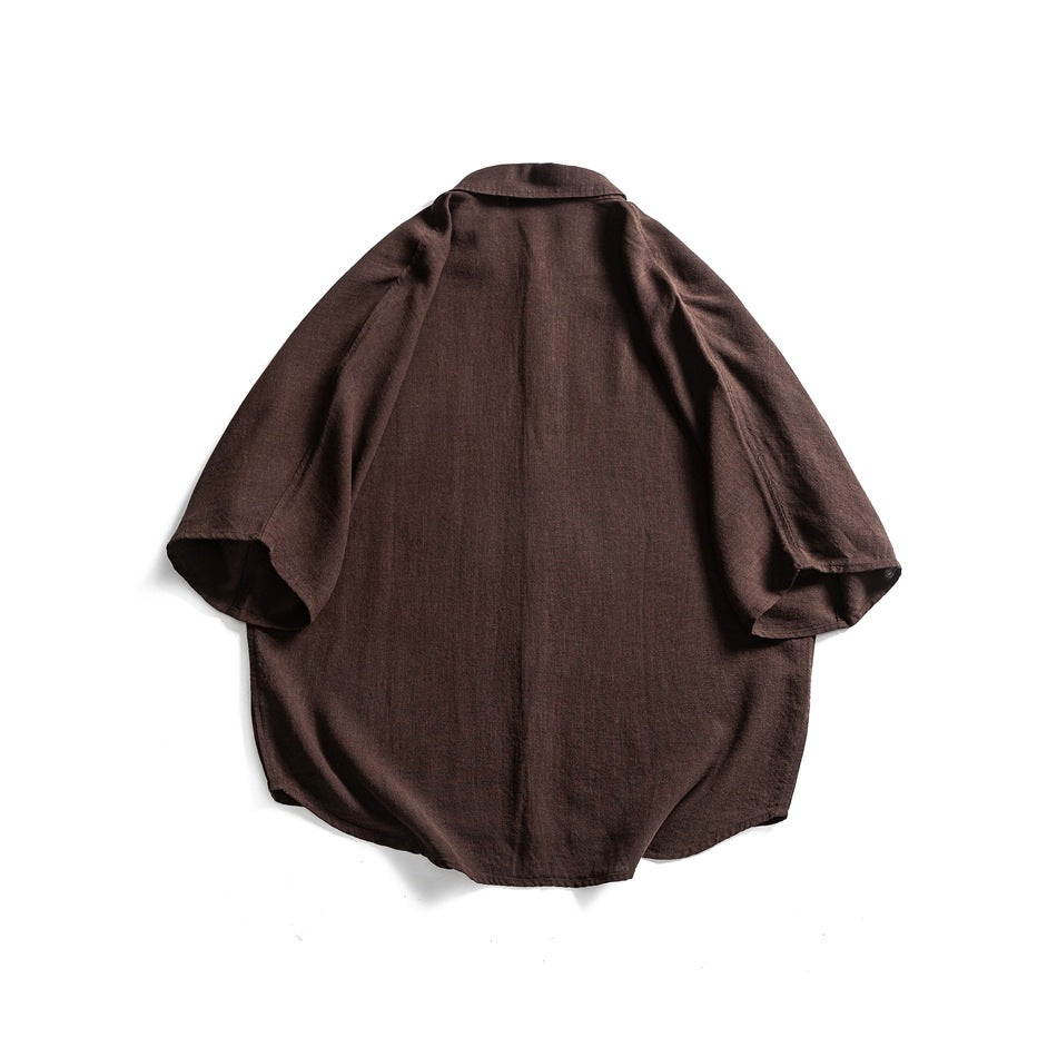 Back view of a dark brown short-sleeve button-up shirt laid flat on white.