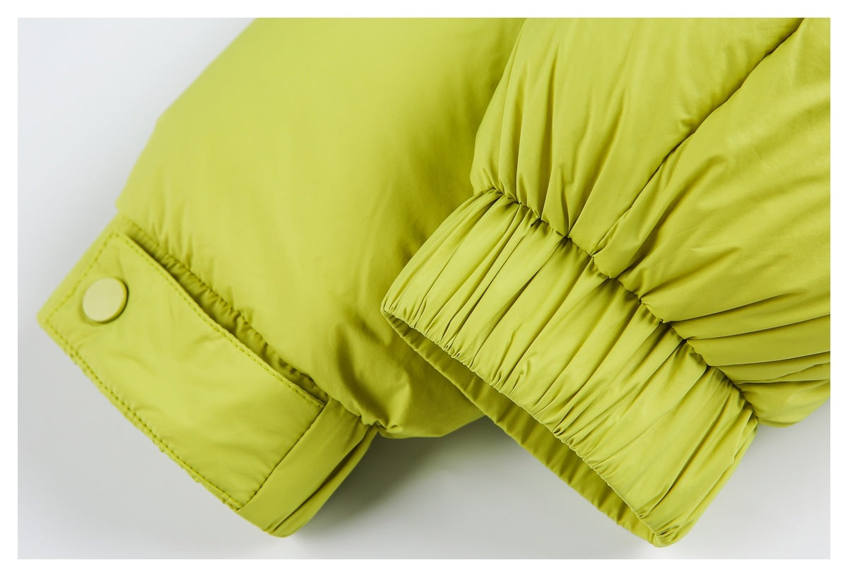 Close-up of a chartreuse padded jacket sleeve cuff with elastic gathering and a snap-tab closure.