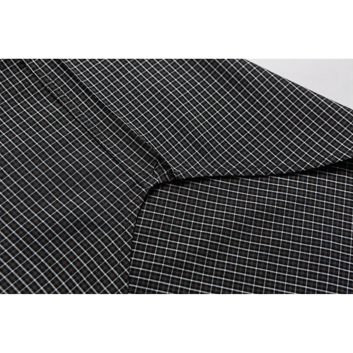 Close-up of a black-and-white checked shirt showing a panel seam and fabric pattern.