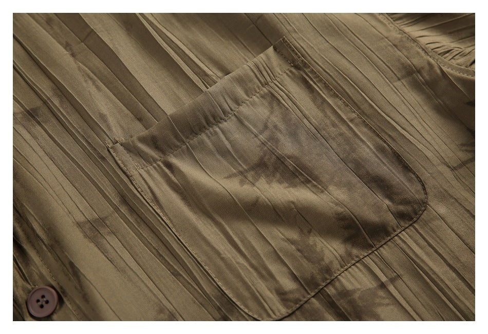 Close-up of a chest pocket on a brown abstract-patterned shirt with vertical stitched lines.