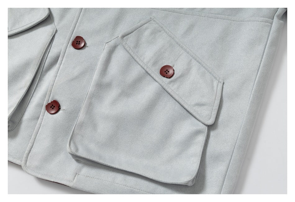 Close-up of a light gray coat's large flap pocket and burgundy buttons.
