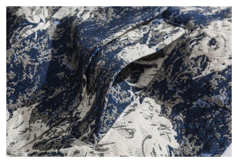 Close-up of blue and ivory floral-patterned fabric folded to show its texture and stitched edge.