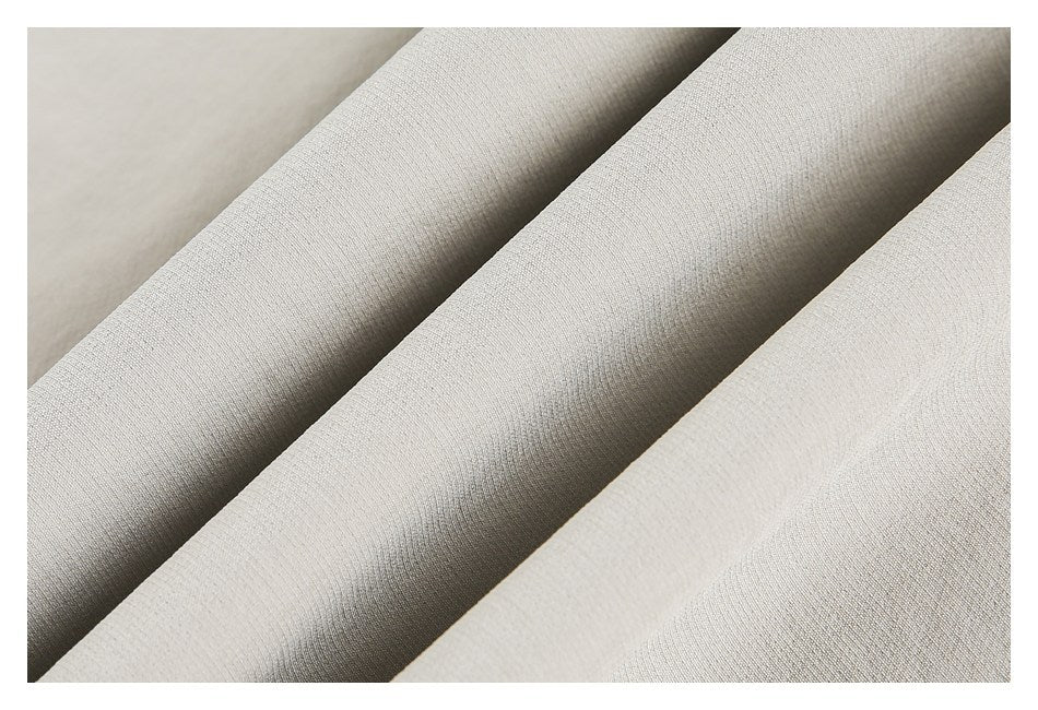 Close-up of light beige fabric arranged in soft folds.