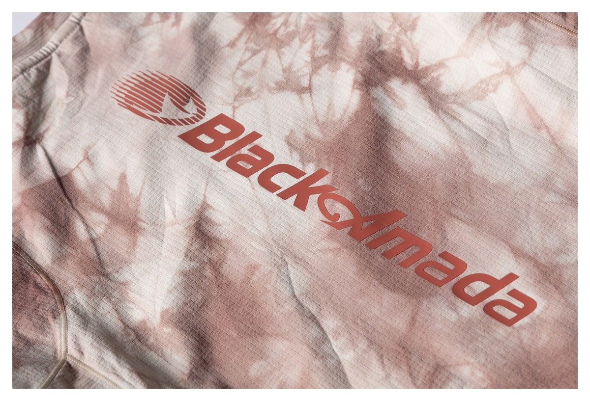 Close-up of a red logo and lettering printed on the cream and dusty-rose tie-dye shirt.