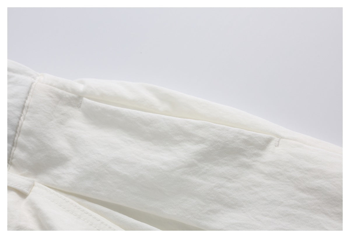 Close-up of off-white trousers showing a side pocket opening and stitched seams.