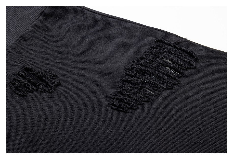 Close-up of two frayed distressed slashes on the black sweatshirt fabric.