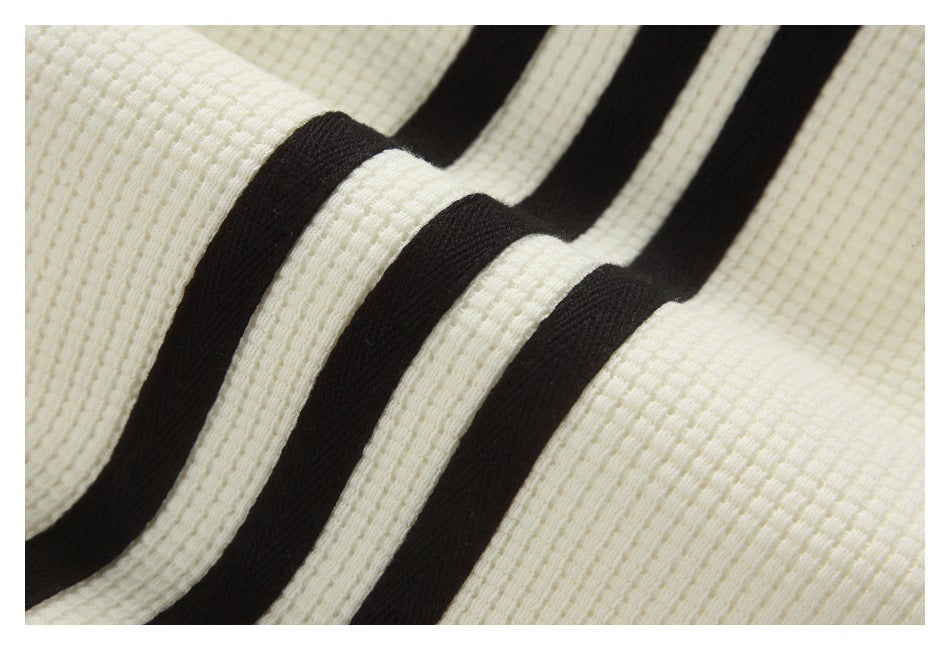 Close-up of curved black stripes against off-white textured fabric.