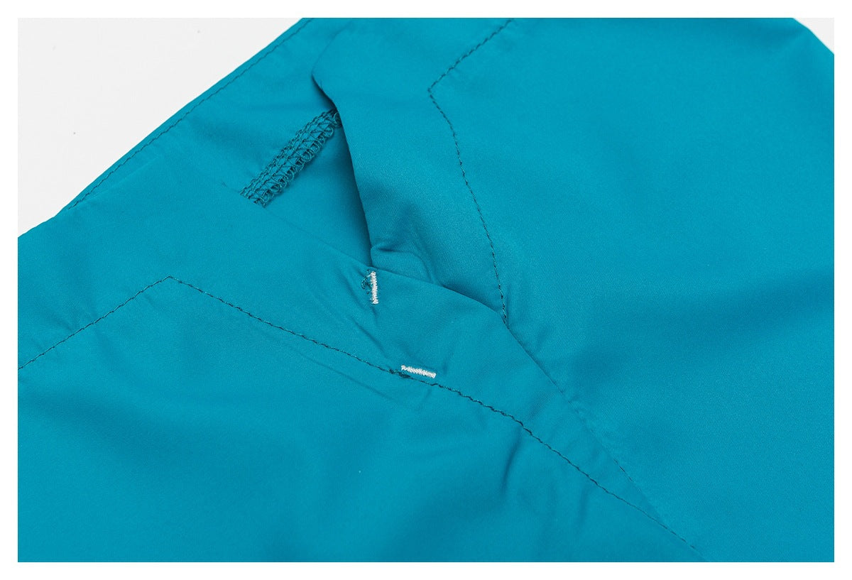 Close-up of turquoise garment seams and two small white buttonholes.