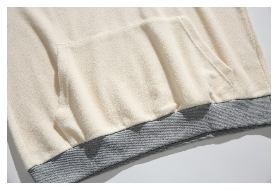 Close-up of a cream garment's large pocket and gray ribbed hem.