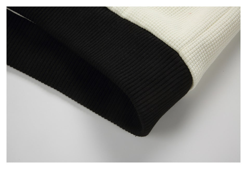Close-up of a black ribbed hem joined to cream textured fabric.