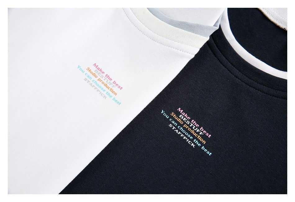 Close-up of white and black crew-neck shirts with small multicolor English text printed on the chest.