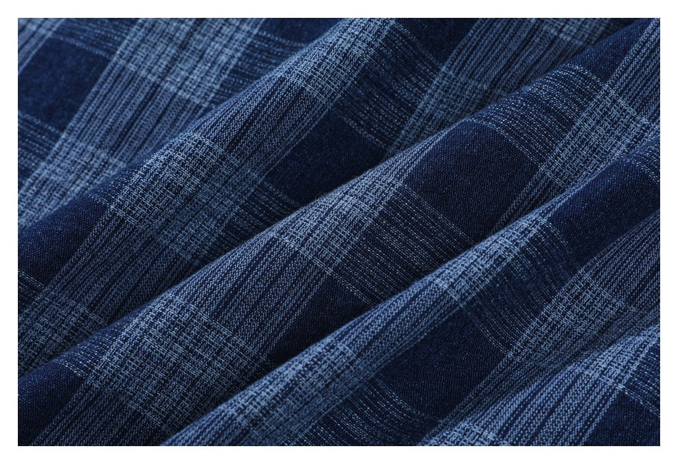 Close-up of navy fabric with a textured light blue plaid pattern and soft folds.