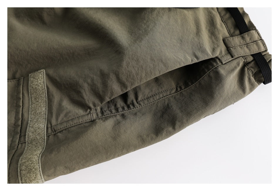 Close-up of the skirt's olive side panel, stitched seam, hook-and-loop tab, and black strap.