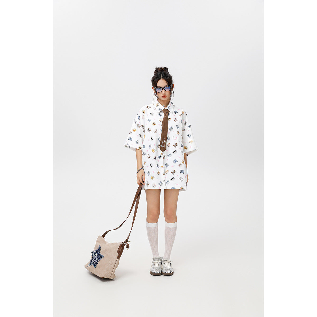Full-length view of a model in an oversized white cat-print shirt with a brown tie, knee socks and sneakers.